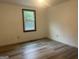 A bedroom with wood-look laminate flooring, a window to the outside, and an electrical outlet at 8833 Thomas Rd, Jonesboro, GA 30238