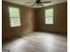 A bedroom with wood paneling, wood-look laminate flooring, two windows, and a ceiling fan with light fixture at 8833 Thomas Rd, Jonesboro, GA 30238