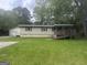 Single-story home featuring a wooden ramp, red trim windows, an adjacent garage, and a sprawling green front lawn at 8833 Thomas Rd, Jonesboro, GA 30238