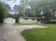 A single-story home showcases an attached garage and ramp access surrounded by a well-maintained lawn and mature trees at 8833 Thomas Rd, Jonesboro, GA 30238
