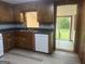 A kitchen featuring wood cabinets, a stainless steel sink and a white dishwasher, with door to an enclosed outdoor space at 8833 Thomas Rd, Jonesboro, GA 30238