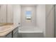 Bathroom featuring a bathtub, a window, and a sink with gray cabinets for storage at 572 Whitman Ln # 19, Stockbridge, GA 30281