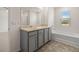 Bathroom showcasing double sinks with gray cabinets, a tub, and a window for natural light at 572 Whitman Ln # 19, Stockbridge, GA 30281