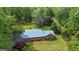 Aerial view of ranch-style home with metal roof, showcasing the well-maintained yard and lush, surrounding greenery at 725 & 761 School Road, Hampton, GA 30228