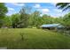 Large green backyard featuring mature trees, with a detached garage and a home with a blue metal roof at 725 & 761 School Road, Hampton, GA 30228