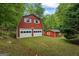 Detached two-story garage featuring two garage doors, white trim and a red exterior, nestled amongst lush trees at 725 & 761 School Road, Hampton, GA 30228