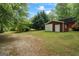 Outbuilding with red exterior and white trim, set in a spacious yard with mature trees and lush greenery at 725 & 761 School Road, Hampton, GA 30228