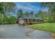 Brick home with a side-entry garage and a long driveway bordered by green foliage and a fenced area at 1349 Springwood Nw Dr, Conyers, GA 30012