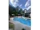 Backyard pool with lounge chairs, patio umbrellas, and a beautifully landscaped perimeter at 374 Persimmon Dr, Sharpsburg, GA 30277