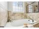 Close up of a bright bathroom showing the soaking tub with tile surround and a window at 108 Turnberry Trce, Sharpsburg, GA 30277