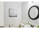 Light-filled half bathroom with classic wainscoting, round mirror and elegant details at 108 Turnberry Trce, Sharpsburg, GA 30277
