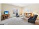 A living room features neutral carpet and walls, a brown couch and two blue chairs, with lots of natural light at 108 Turnberry Trce, Sharpsburg, GA 30277