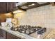 Close-up of the cooktop featuring granite countertops and tile backsplash at 108 Turnberry Trce, Sharpsburg, GA 30277