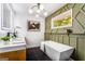 Modern bathroom featuring a standalone tub, decorative green wall, and stylish lighting fixtures at 2019 Emerald Dr, Jonesboro, GA 30236