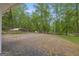 Gravel driveway with parking area and surrounding trees at 7616 Nicholson Rd, Cumming, GA 30028