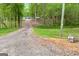 View of the long driveway with a home, pond, and lush trees at 7616 Nicholson Rd, Cumming, GA 30028