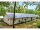 Back exterior view of home with neutral siding, metal roof, small patio, lawn, and green shrubbery at 7616 Nicholson Rd, Cumming, GA 30028