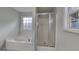 Bathroom featuring a white tub next to window, and an enclosed shower with glass doors and chrome trim at 321 Shadowbrooke Dr, Loganville, GA 30052