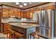 Well-lit kitchen with stainless steel refrigerator, wooden cabinets, granite counters, and an island with seating at 171 Wynn Dr, Hampton, GA 30228