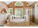 Bright bathroom features a soaking tub under a window and a tiled shower with glass door at 139 Crown Forest Dr, Mcdonough, GA 30252