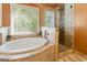 Bright bathroom features a soaking tub under a window and a tiled shower with glass door at 139 Crown Forest Dr, Mcdonough, GA 30252