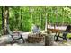Stone-lined firepit with Adirondack chairs, log stools, and lush green surroundings for outdoor gatherings at 139 Crown Forest Dr, Mcdonough, GA 30252
