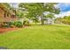 Backyard featuring a lush green lawn, mature trees, shed, and charming white picket fence at 110 Silver Leaf Dr, Fayetteville, GA 30214