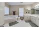 Large bathroom featuring double sinks, a soaking tub, and ample storage space with natural light from a window at 8040 Classic Dr, Jonesboro, GA 30236