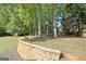 Expansive backyard with a playground and storage building, surrounded by mature trees and a retaining wall at 1310 Yarborough Dr, Peachtree City, GA 30269