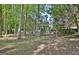 Backyard featuring a swing set surrounded by mature trees and a wooden fence at 1310 Yarborough Dr, Peachtree City, GA 30269