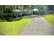 A well-maintained home with a carport and long driveway, surrounded by a green lawn and trees at 1655 Tryon Ne Rd, Brookhaven, GA 30319