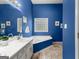 A vivid blue bathroom with a separate shower and a soaking tub with natural light at 190 Ridgecrest Dr, Fayetteville, GA 30215