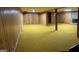 Unfinished basement with paneled walls, dated carpet and a brick fireplace at 8315 Ridge Rd, Fairburn, GA 30213