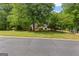 Home's exterior from the street is enhanced by mature trees and landscaped lawn, showcasing its curb appeal at 40 High St, Sharpsburg, GA 30277