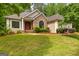 Stunning front exterior with stone accents, red door, manicured lawn, and mature trees, creating great curb appeal at 40 High St, Sharpsburg, GA 30277