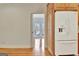 Kitchen with wood cabinets, a white refrigerator, and hardwood floors; view into another room at 40 High St, Sharpsburg, GA 30277