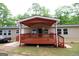 Rear exterior showcasing a covered porch, vinyl siding, and trees in the background at 208 Holliday Way, Carrollton, GA 30116