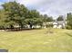 Spacious front yard with mature trees and a charming two-story home in the background at 3550 N Bogan Rd, Buford, GA 30519