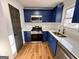 This kitchen features stainless steel appliances, new granite countertops, and sleek blue cabinets at 473 Amy Blvd, Temple, GA 30179