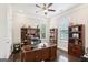 A home office with wooden floors, a ceiling fan, built in bookshelves, and natural light from two windows at 175 Campaign Trl, Fayetteville, GA 30214