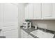 A bright laundry room featuring gray granite counters, white cabinetry, and a utility sink at 175 Campaign Trl, Fayetteville, GA 30214