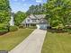 Aerial view of the home, landscaping, driveway, and garage surrounded by trees and green grass at 3129 Oak Ridge Ln, Loganville, GA 30052