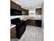 Modern kitchen featuring sleek dark cabinets, stainless steel appliances, and durable gray tile flooring at 4712 Rockstile Way, Stone Mountain, GA 30083