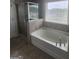 Bathroom featuring a large soaking tub with tiled walls, a window, and a glass enclosed shower at 883 Ironhorse Sw Ln, Mableton, GA 30126