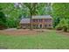 Attractive two-story brick house with black shutters surrounded by lush greenery and a well-maintained lawn at 120 Hermitage Pl, Peachtree City, GA 30269