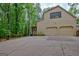 Beige two-story home featuring a two-car garage and a concrete driveway flanked by lush trees at 120 Hermitage Pl, Peachtree City, GA 30269