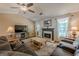 Cozy living room with a fireplace, plush seating, and a ceiling fan for comfortable living at 5045 Edinborough Pl, Sugar Hill, GA 30518