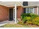 Charming brick home featuring a covered front porch with column, manicured landscaping, and a screen door at 140 Braymoor Cir, Fayetteville, GA 30215