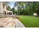 View from the backyard featuring the wooden deck, stone patio, and lush green lawn at 100 Hartford Pl, Fayetteville, GA 30214