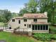 Backyard featuring a wooden deck, stone patio, screened-in porch, lush green lawn, and mature trees at 100 Hartford Pl, Fayetteville, GA 30214